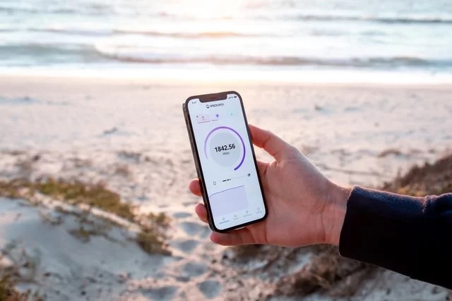 Personne qui regarde la vitesse de sa connexion internet sur son téléphone sur la plage.