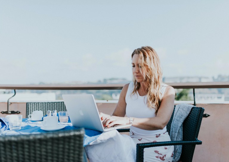 Assistante virtuelle travaillant sur la terrasse d'un café