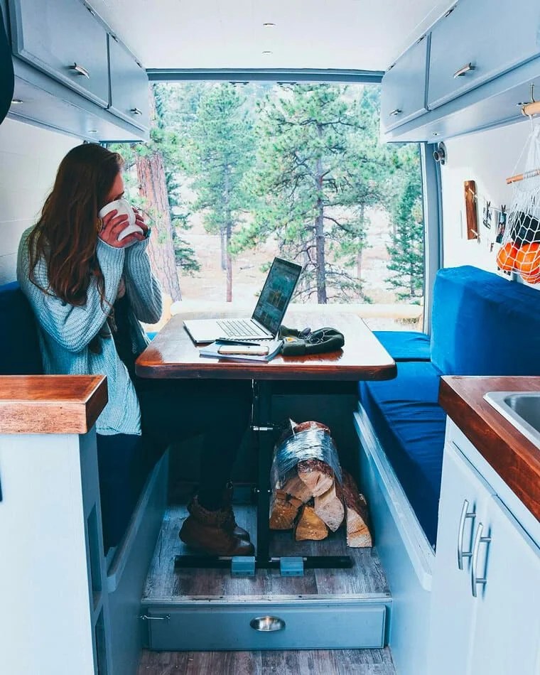 femme buvant son café en travaillant depuis son ordi dans son van aménagé