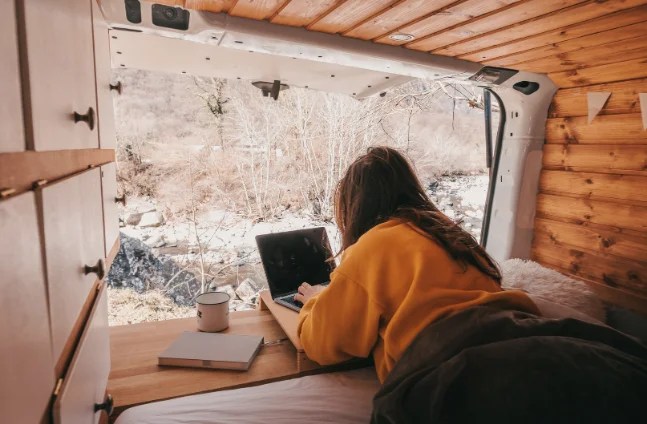 femme qui travaille dans son lit en van