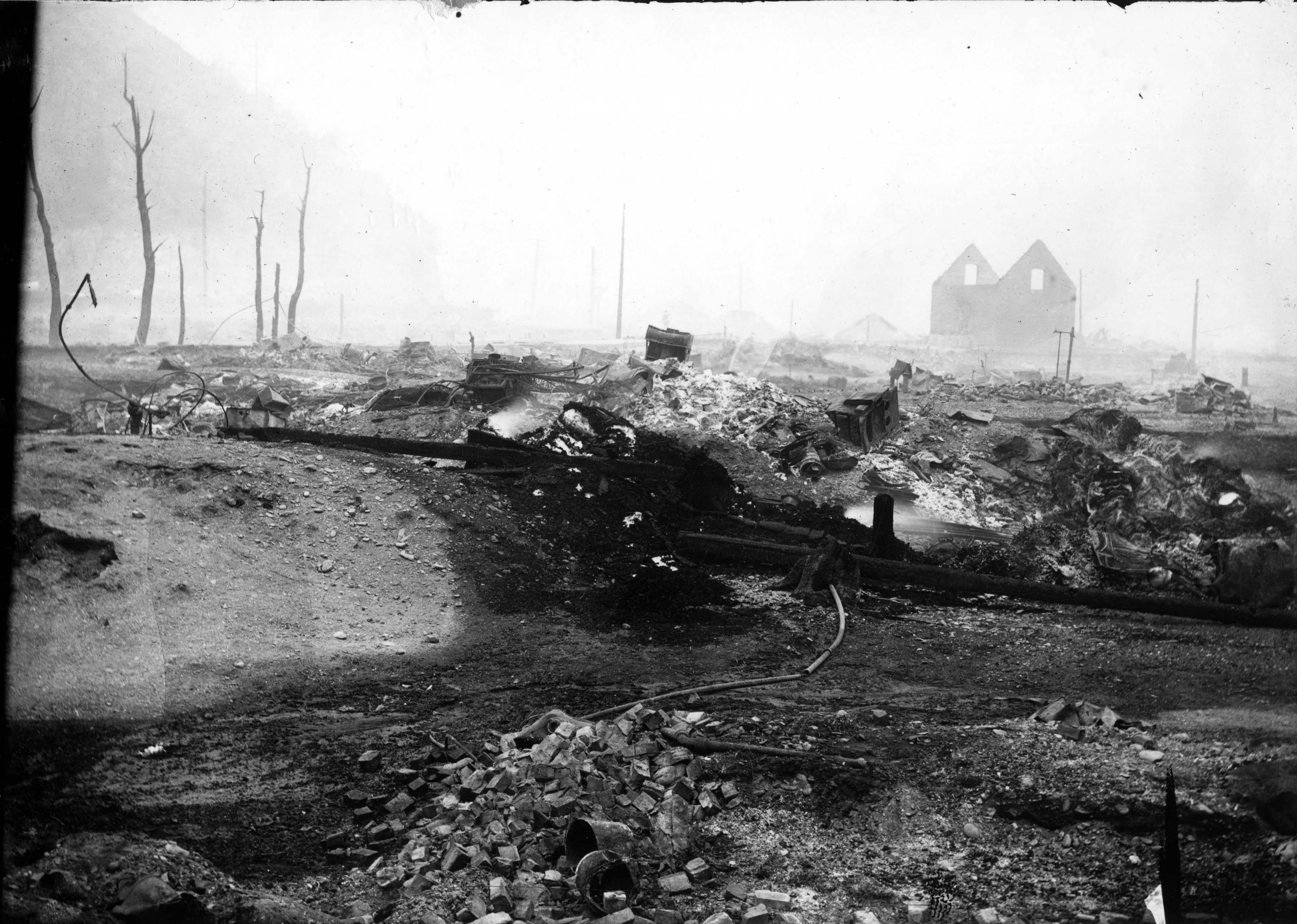Ruins of the Pacific Hotel district in Wallace after the 1910 Big Burn, with brick, timber and machinery scattered through the burned block.