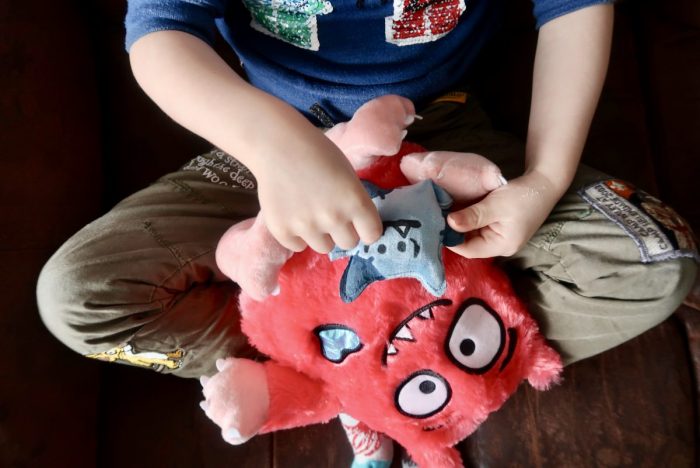 A boy playing with a Love Monster toy on his lap