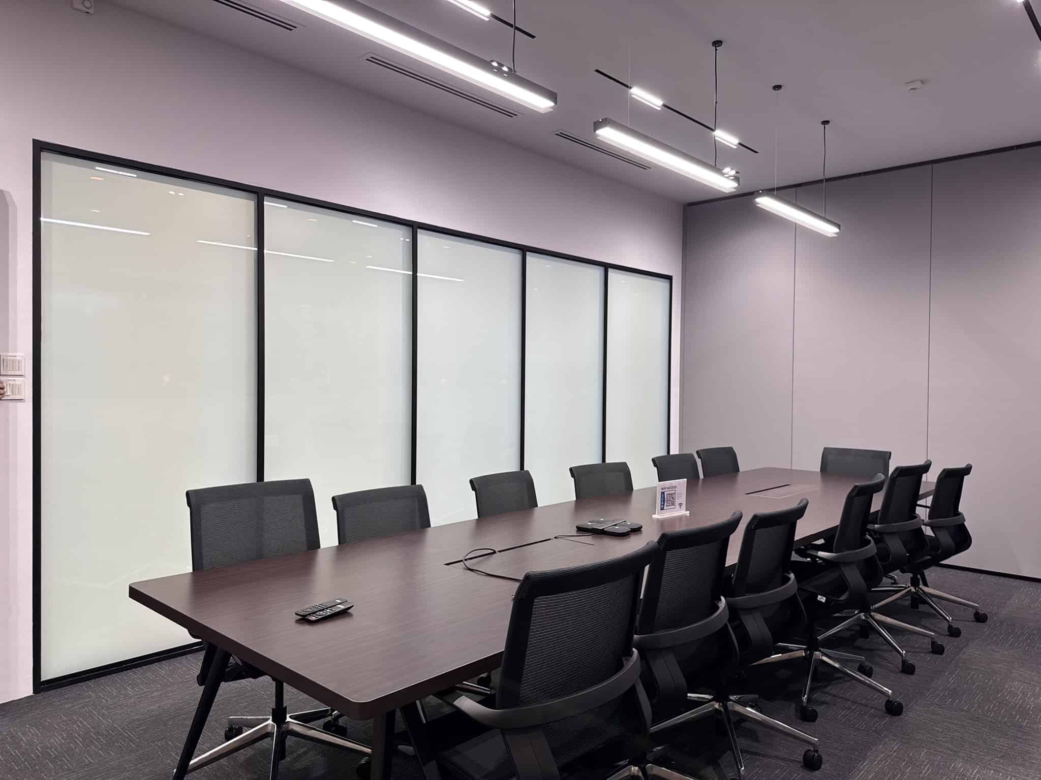 Meeting room with a boardroom table, mesh chairs and a frosted glass partition wall