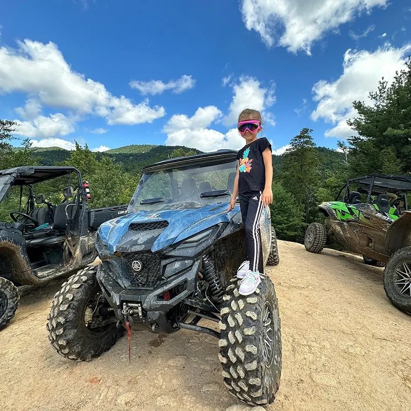 Child standing on the wheel of a side-by-side during an Off-Road Tour