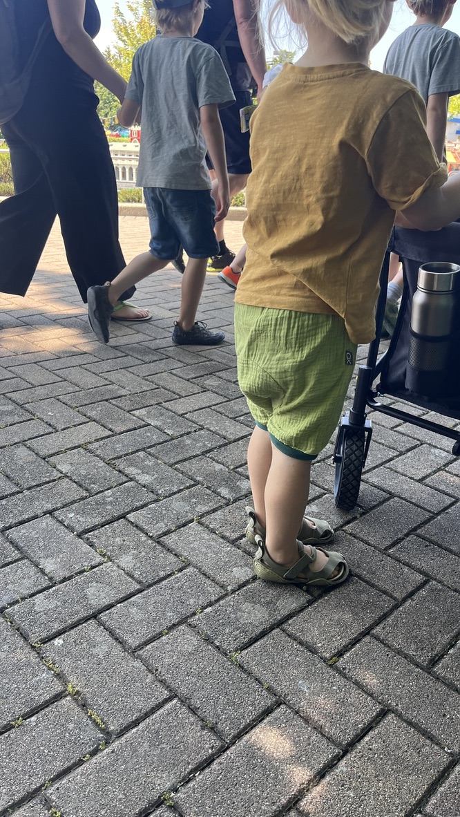 Kind steht mit Windelweg Shorts am Bollerwagen