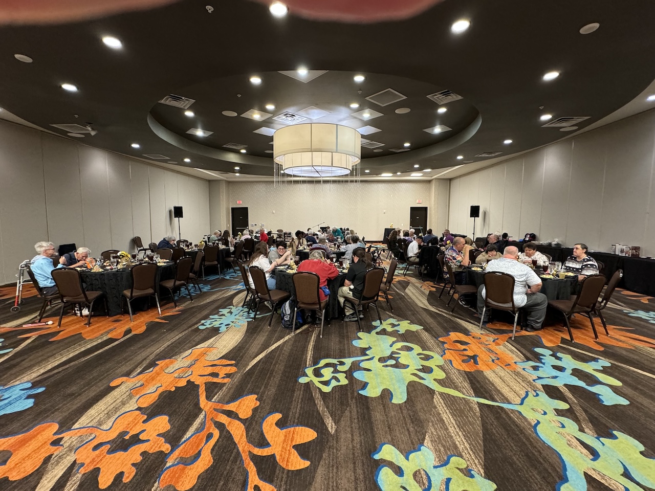 A view of the banquet room with several tables of people getting ready to eat.