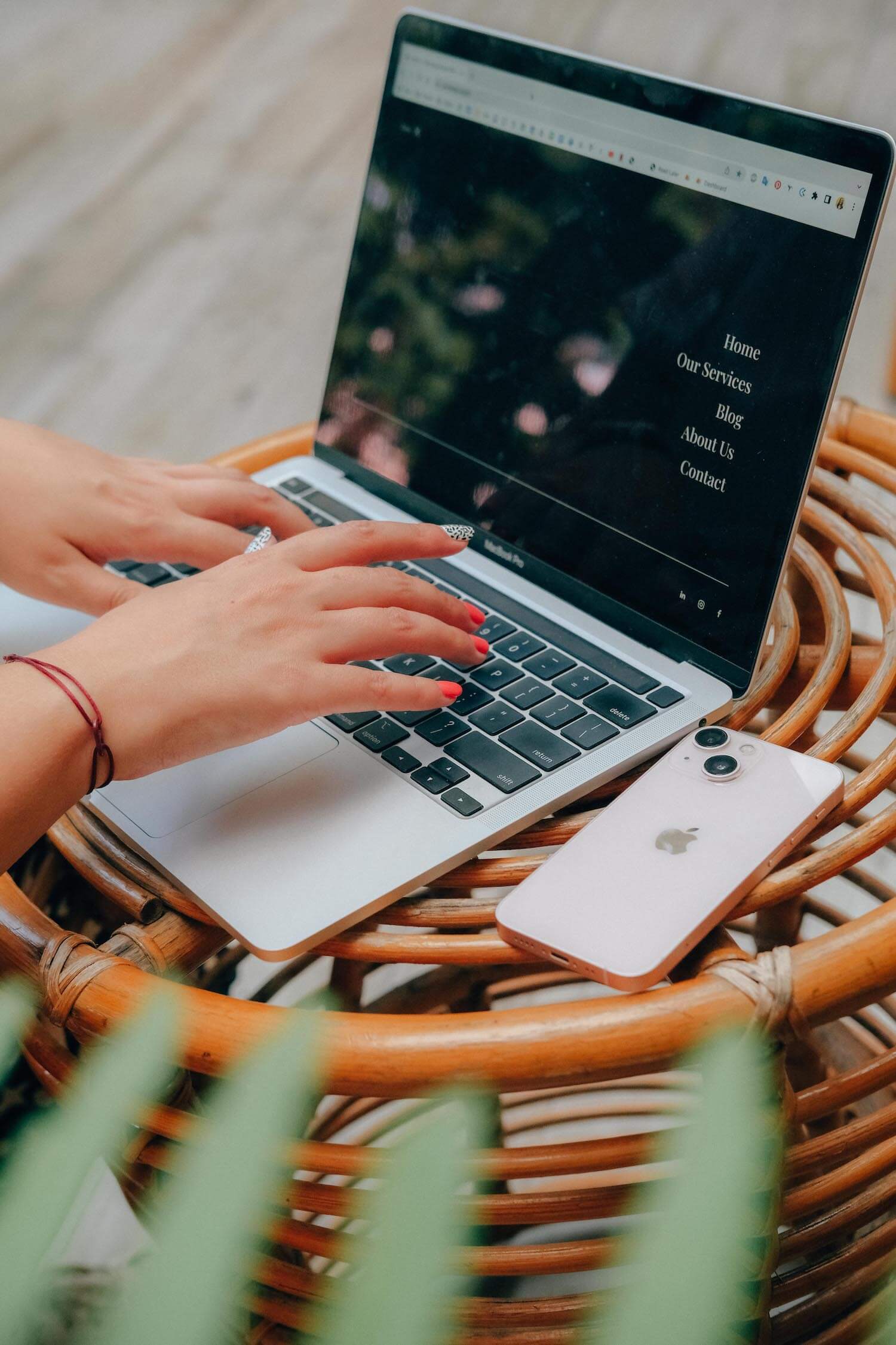 White woman's hand with pink nails typing on a silver Macbook