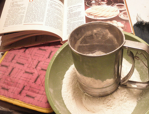 Vintage baking setup with flour sifter, measuring bowl, and classic Maryland cookbook open to recipe page for Sotterley Jumbles