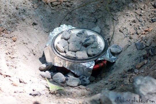 Cast iron Dutch oven with hot coals for beef à la mode cooking buried in earth for slow cooking outdoors