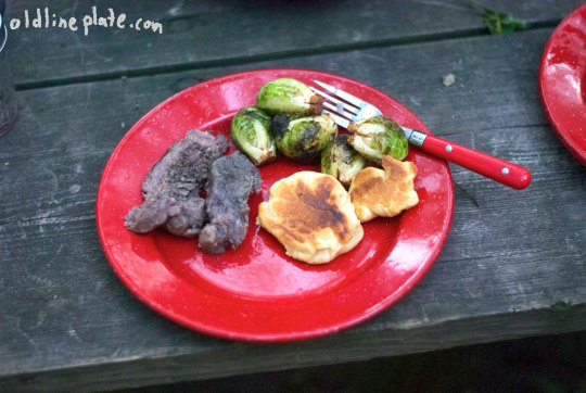 Beef à la Mode plated with roasted Brussels sprouts and biscuits on red camping plate