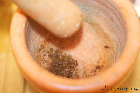 Grinding spices in mortar and pestle for beef à la mode recipe preparation