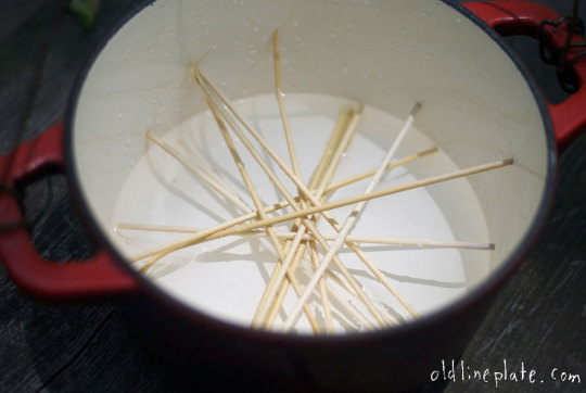 Wooden skewers arranged in white dutch oven for beef à la mode recipe preparation