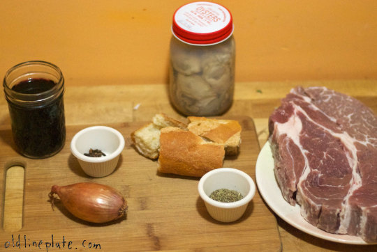 Beef à la Mode ingredients laid out on wooden board including raw meat, bread, onion, spices, wine, and oysters