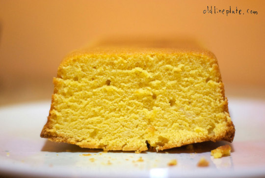 Sliced golden vanilla butternut pound cake on white plate with crumbs