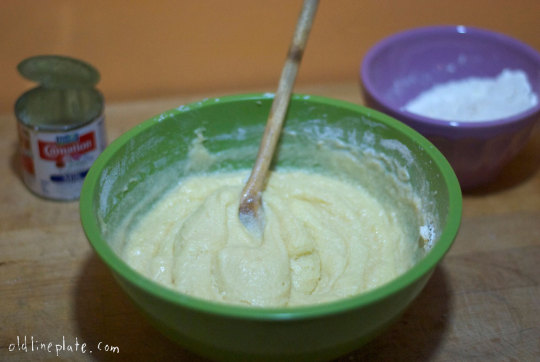 Vanilla butternut pound cake batter mixed in green bowl with ingredients and measuring spoon nearby