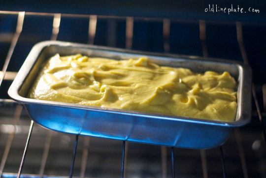 Vanilla butternut pound cake batter in blue loaf pan baking in oven