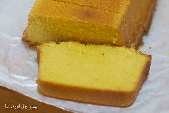 Sliced vanilla butternut pound cake showing golden-brown exterior and tender yellow crumb texture on white parchment paper