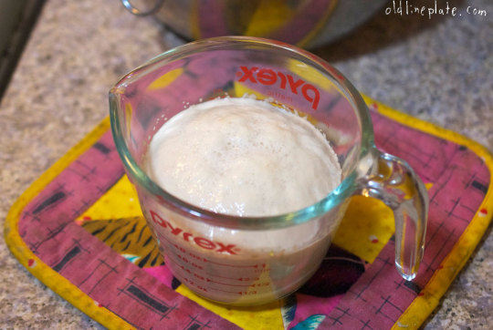 Measuring cup of proofing yeast with measuring spoons on colorful kitchen towel for Fastnachts Küchlie recipe