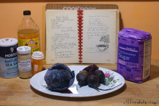 Beets, cabbage and ingredients with open cookbook, horseradish, mustard, salt, and sugar on wooden surface