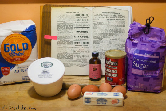 Vintage baking ingredients for Silver Cake recipe including eggs, sugar, baking powder, and Gold Medal flour on wooden surface