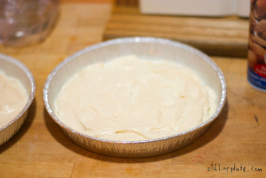 Unbaked silver cake filling in aluminum pie tin on wooden surface