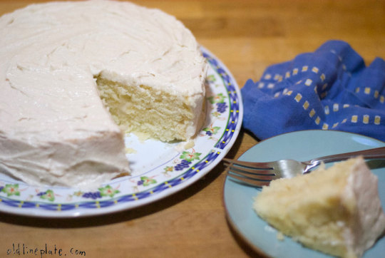 Homemade silver cake with white frosting sliced on decorative plate with fork