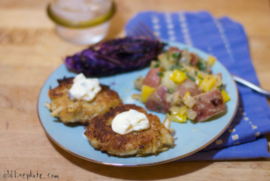 Homemade crab cakes with tartar sauce dollop roasted beets, and potato salad  on blue plate