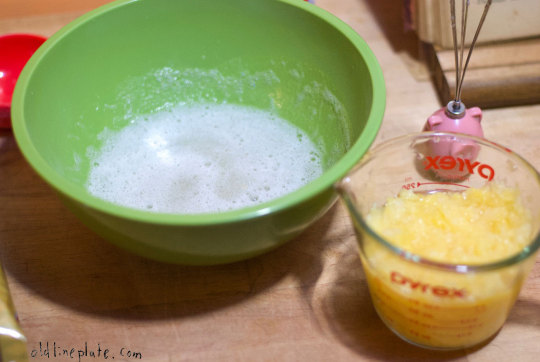 Baking ingredients for pineapple icebox cake with whipped egg whites in green bowl and crushed pineapple in glass measuring cup