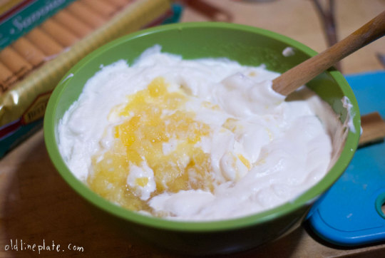 Whipped cream folded with crushed canned pineapple in green bowl for icebox cake dessert