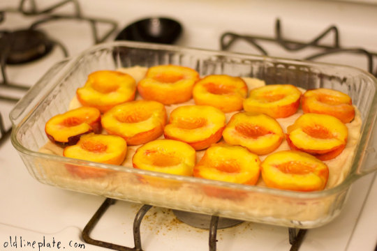 Sliced fresh peaches arranged in glass baking dish for homemade Baltimore peach cake recipe