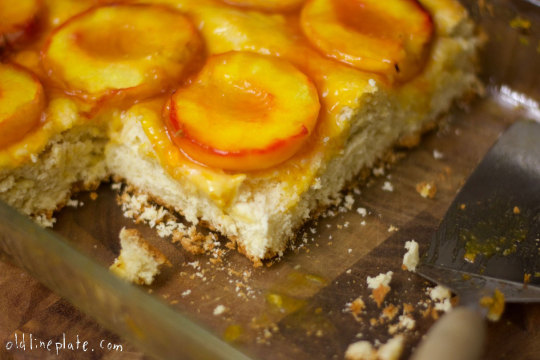 Homemade Baltimore peach cake with glazed peach slices on buttery cake base, sliced and ready to serve