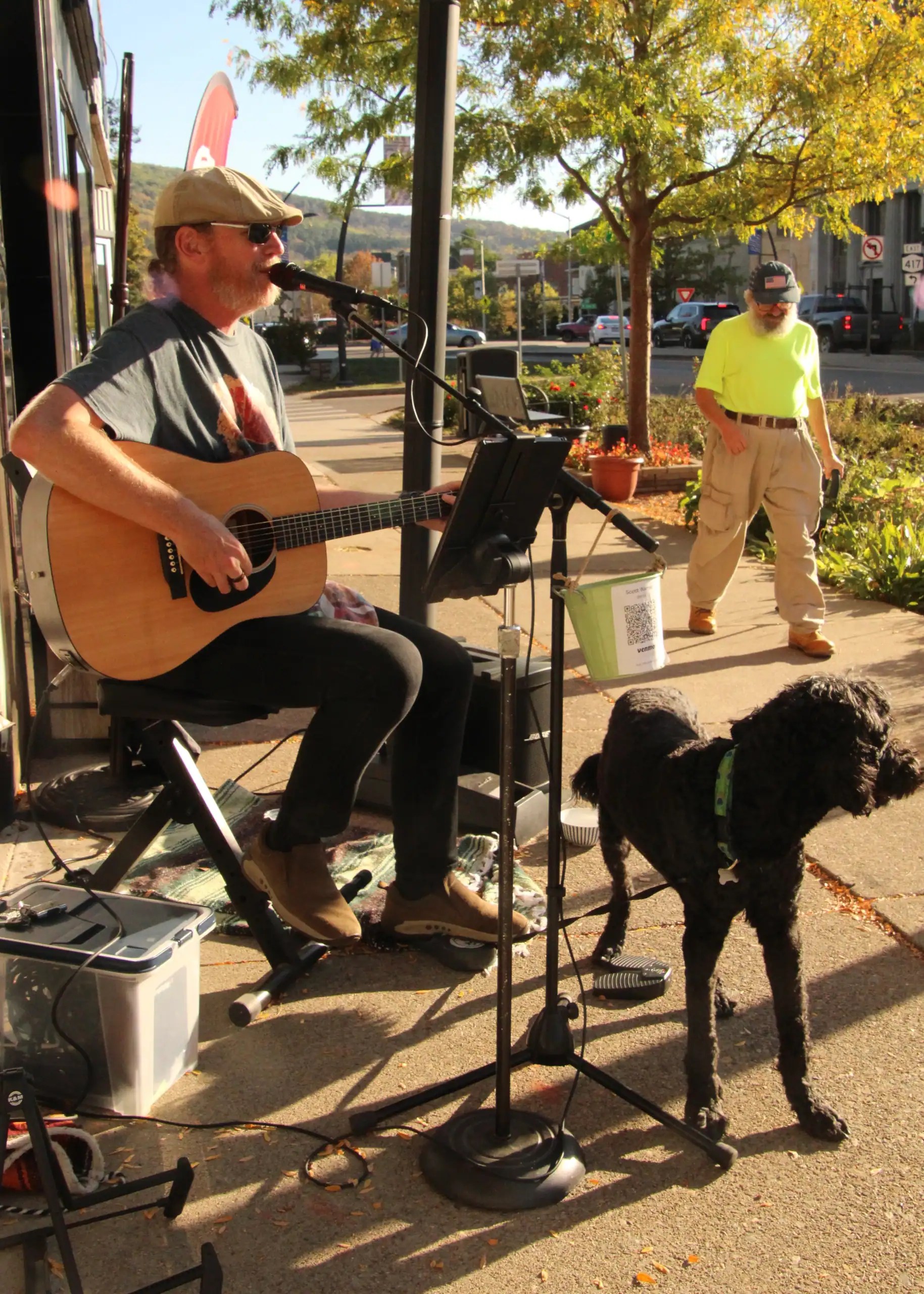 (Rick Miller/Olean Star) Scott Warner of Olean plays guitar and sings outside of Color It Creative, 124 N. Union St., Olean during the last Uptown Olean Music and Art Walk Friday. Walking by is Tony Costa.