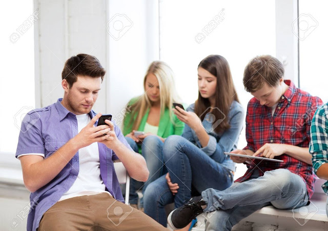 education and internet concept - students looking into phones and tablet pc