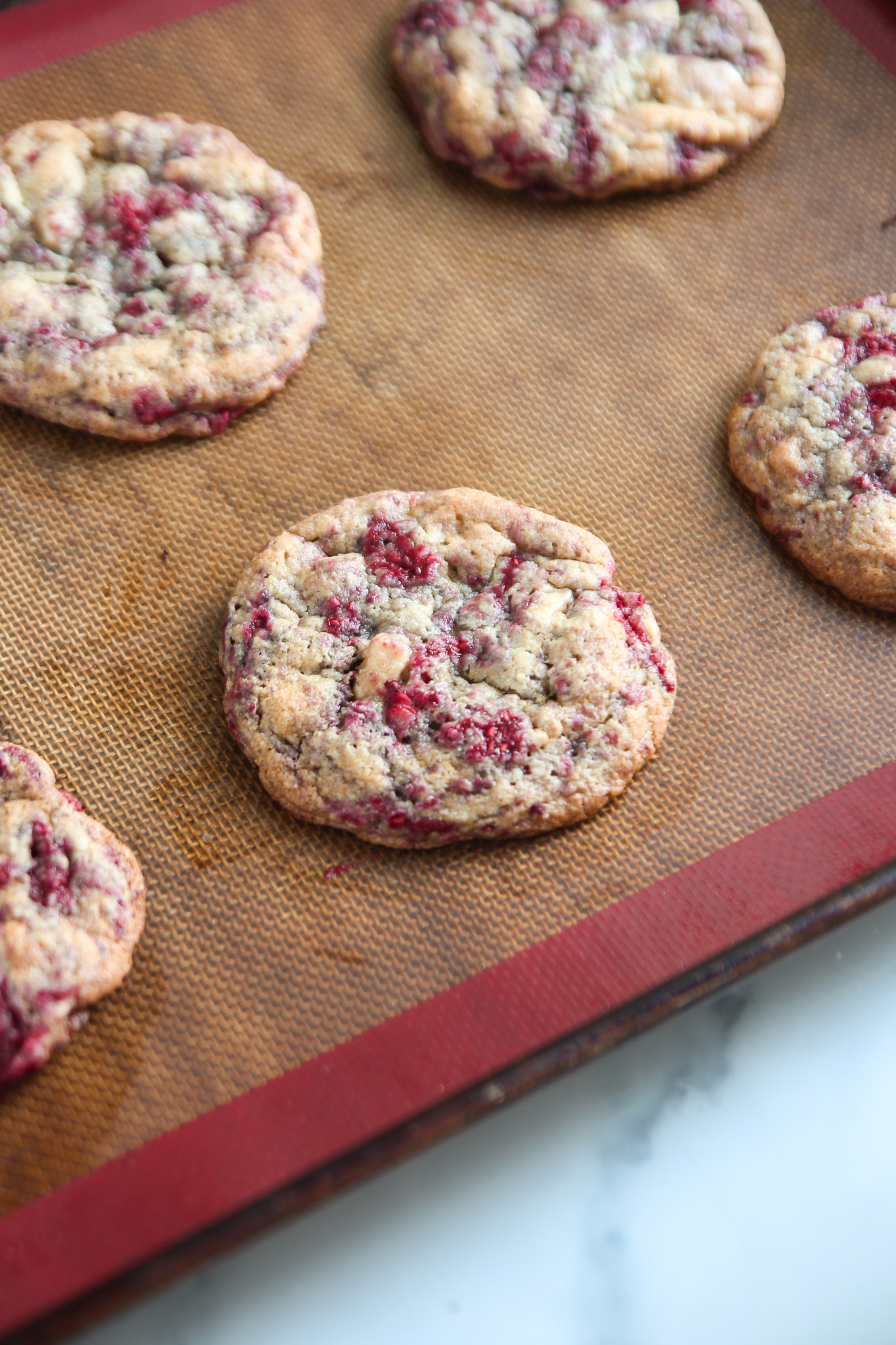 White chocolate and raspberry cookies on a baking tray.