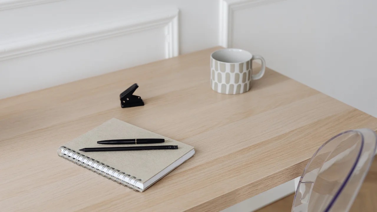 Beige desk set-up with a white coffee mug and notebook with notes about how to start a website on a budget as a private practice owner