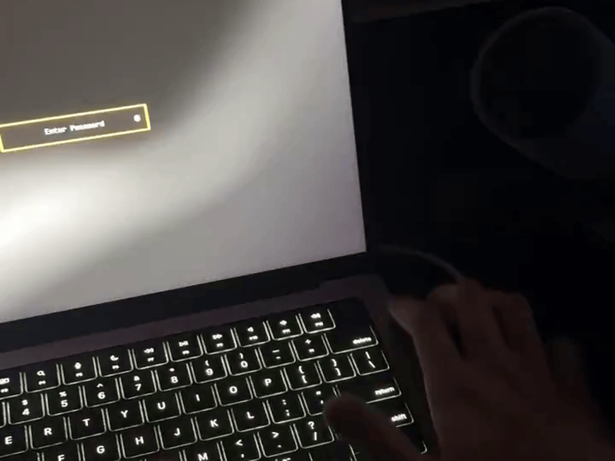 A MacBook Pro with Apple Silicon running the Omarchy Linux desktop shows an 'Enter Password' prompt as a hand reaches for the Touch ID key.