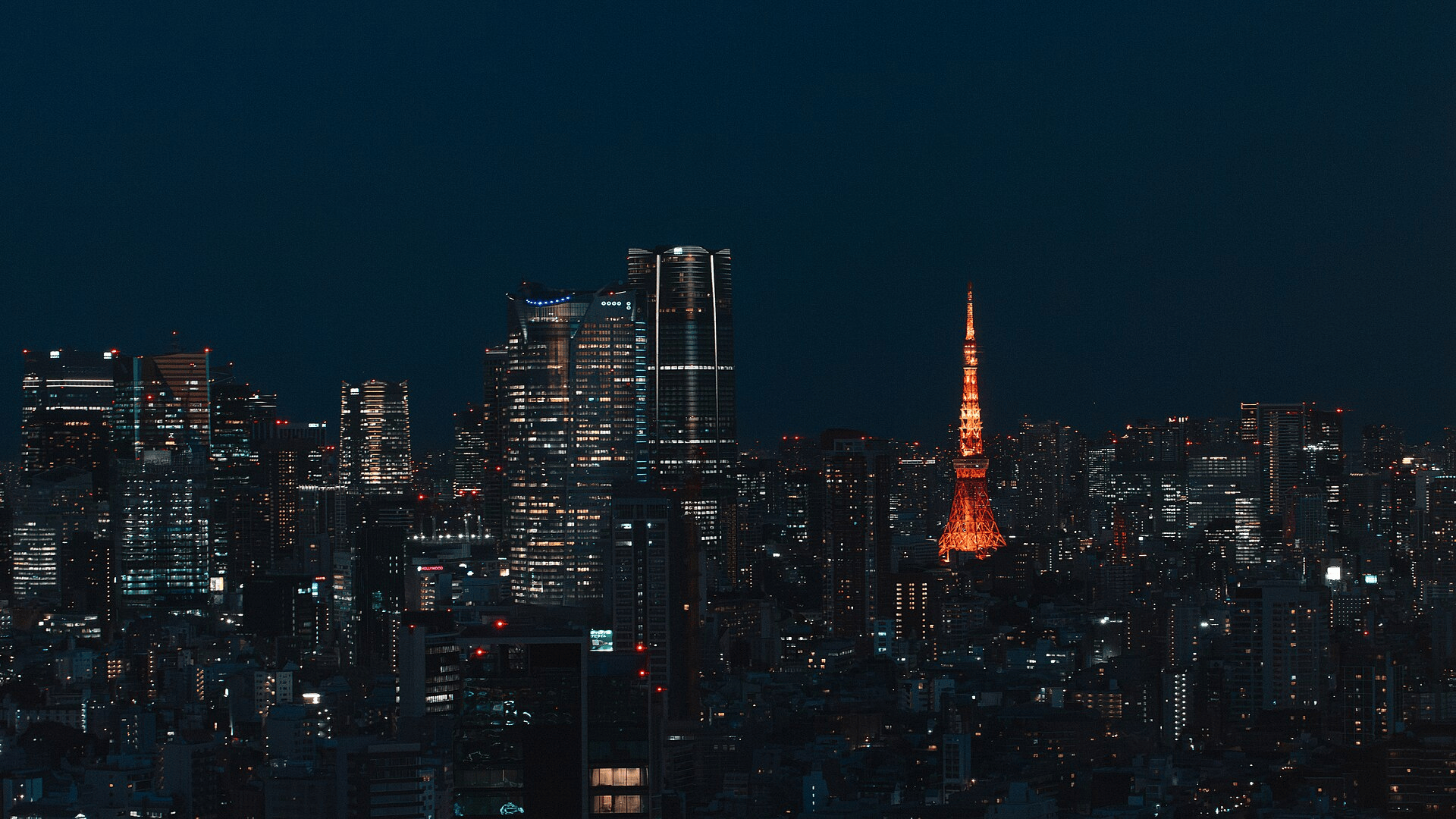 The Minato City skyline in Tokyo at night, with lit office towers spreading toward the horizon.