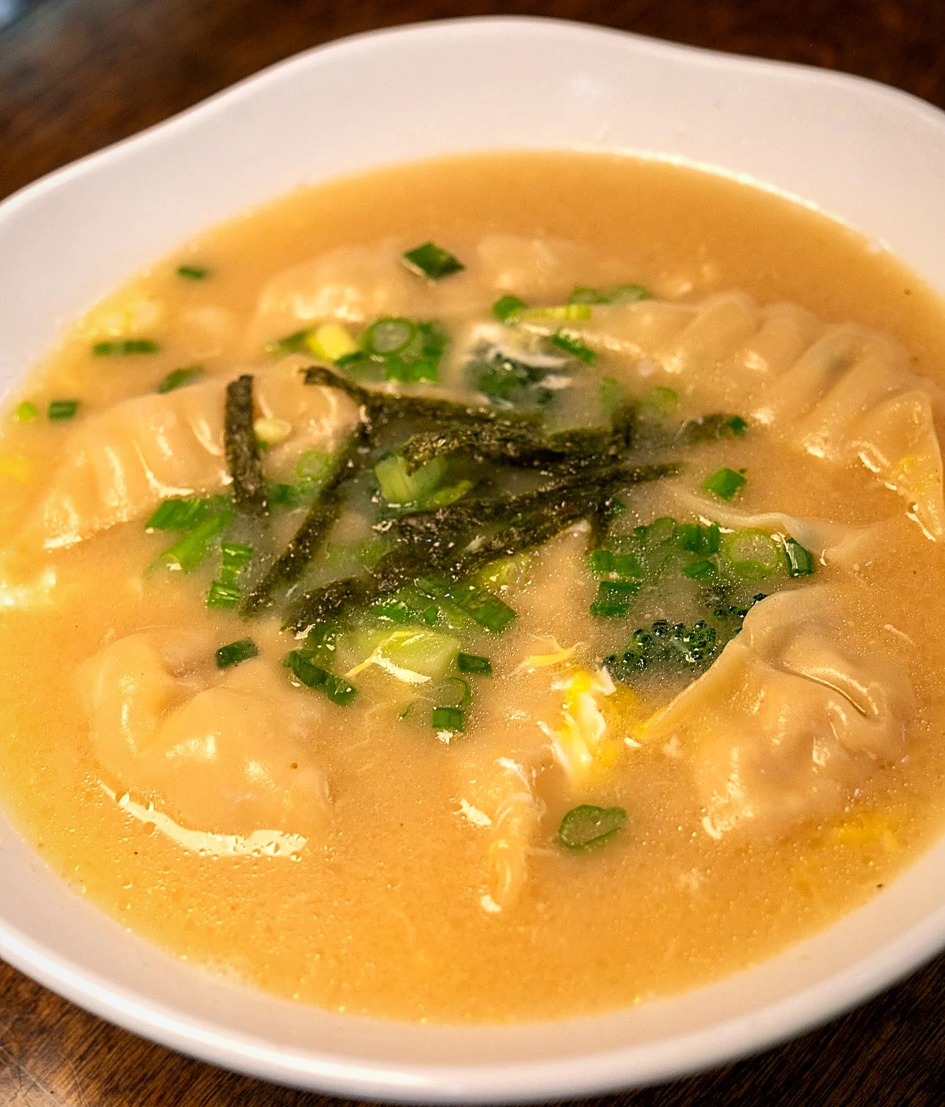 Dumpling soup in savory broth with scallions and nori