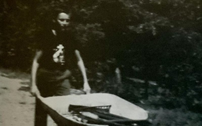 Person pushing a wheelbarrow outdoors.