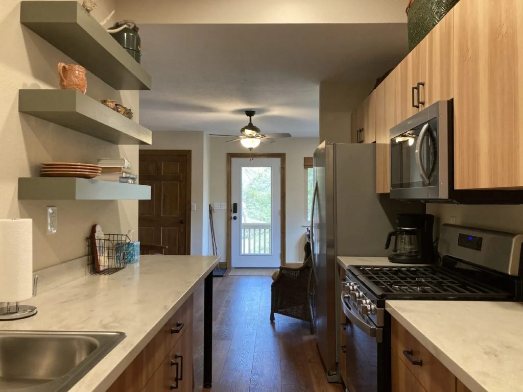 Kitchen with shelves, appliances, and wood floors.