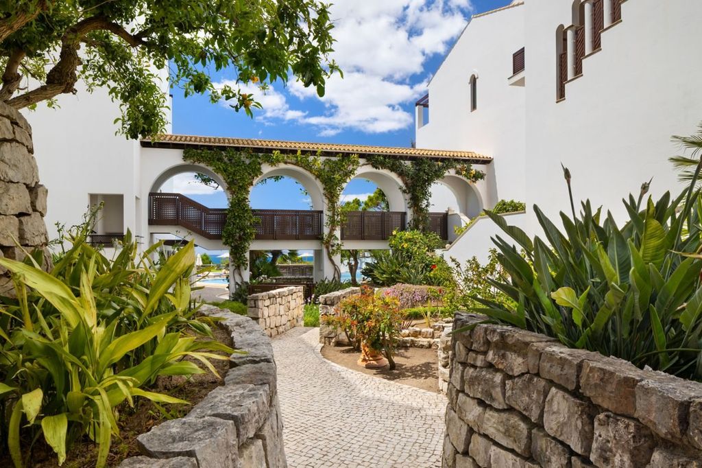 Stone archway framing the garden path and sea view at Pine Cliffs Resort, Algarve
