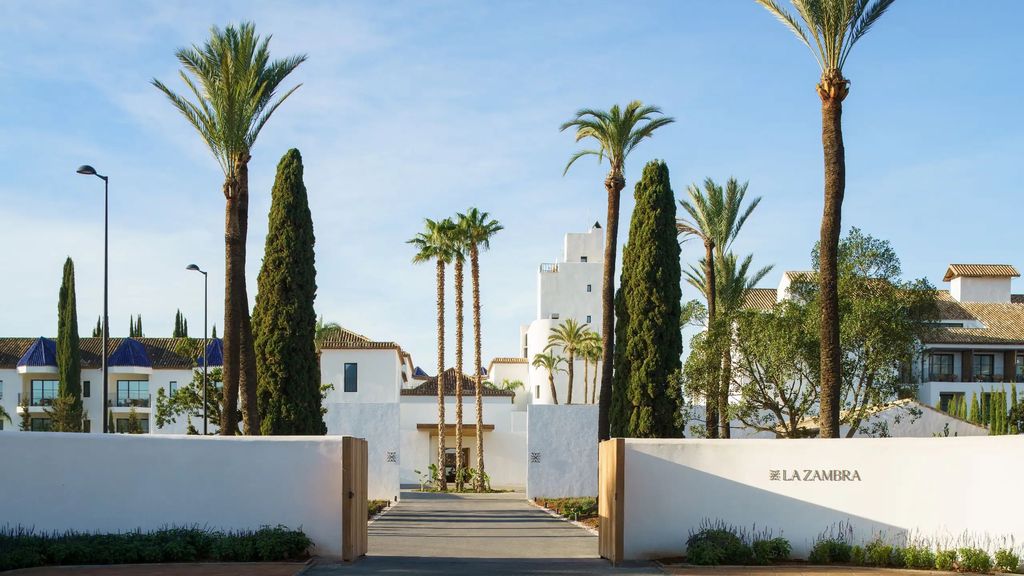 The entrance to La Zambra, with the resort's name on the gate and palm-lined walkway beyond