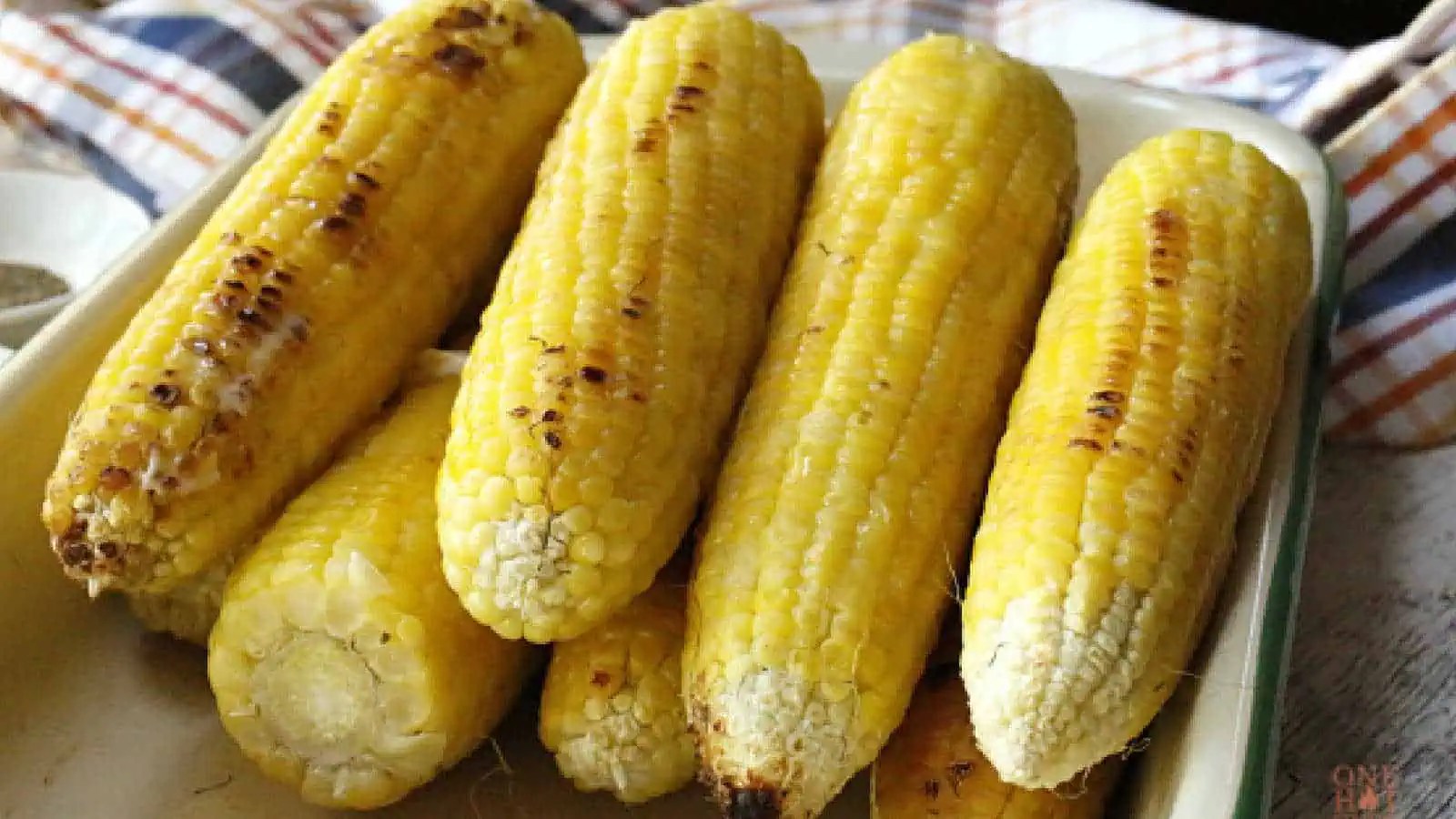 Grilled corn on the cob served on a white platter.