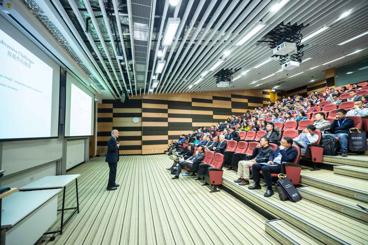 man standing in front of people sitting on red chairs