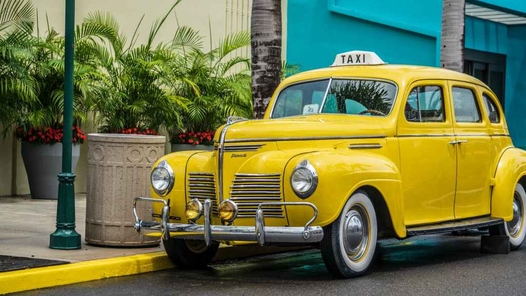 photo of yellow taxi parked near sidewalk