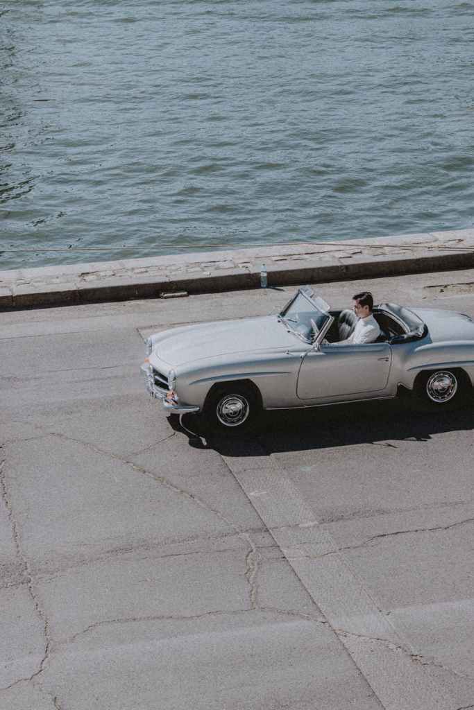 man in white shirt travelling in silver car