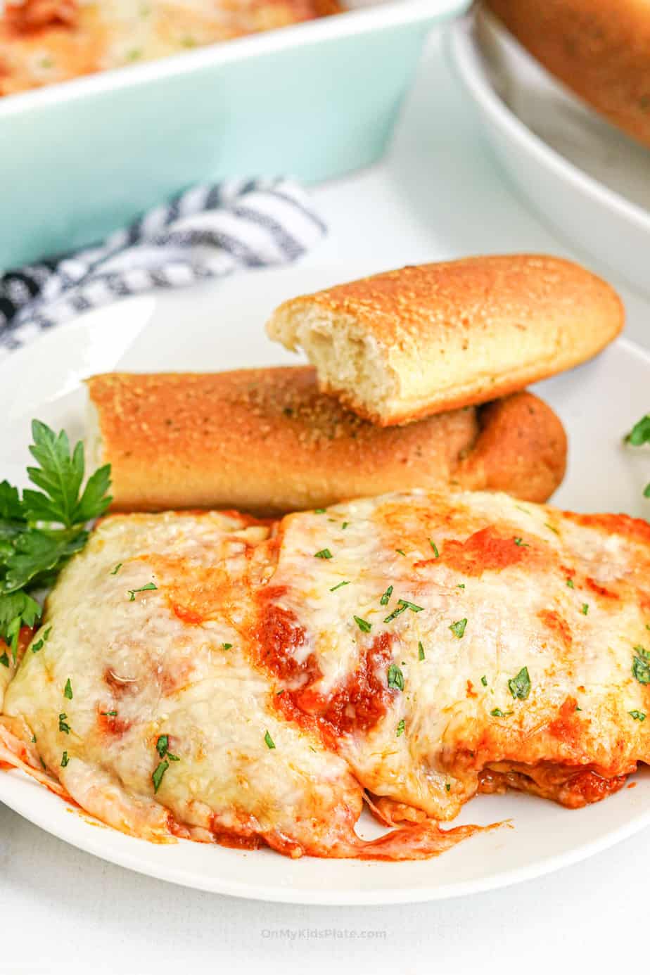 Baked ravioli casserole served on a plate with breadsticks.