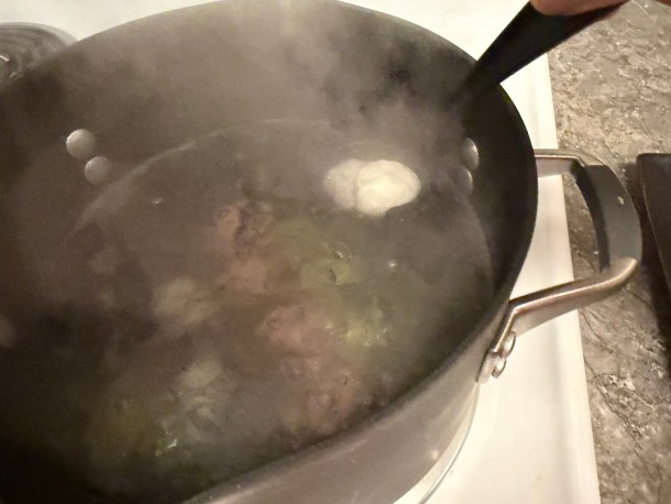 Lowering dough balls into the boiling pot of water.