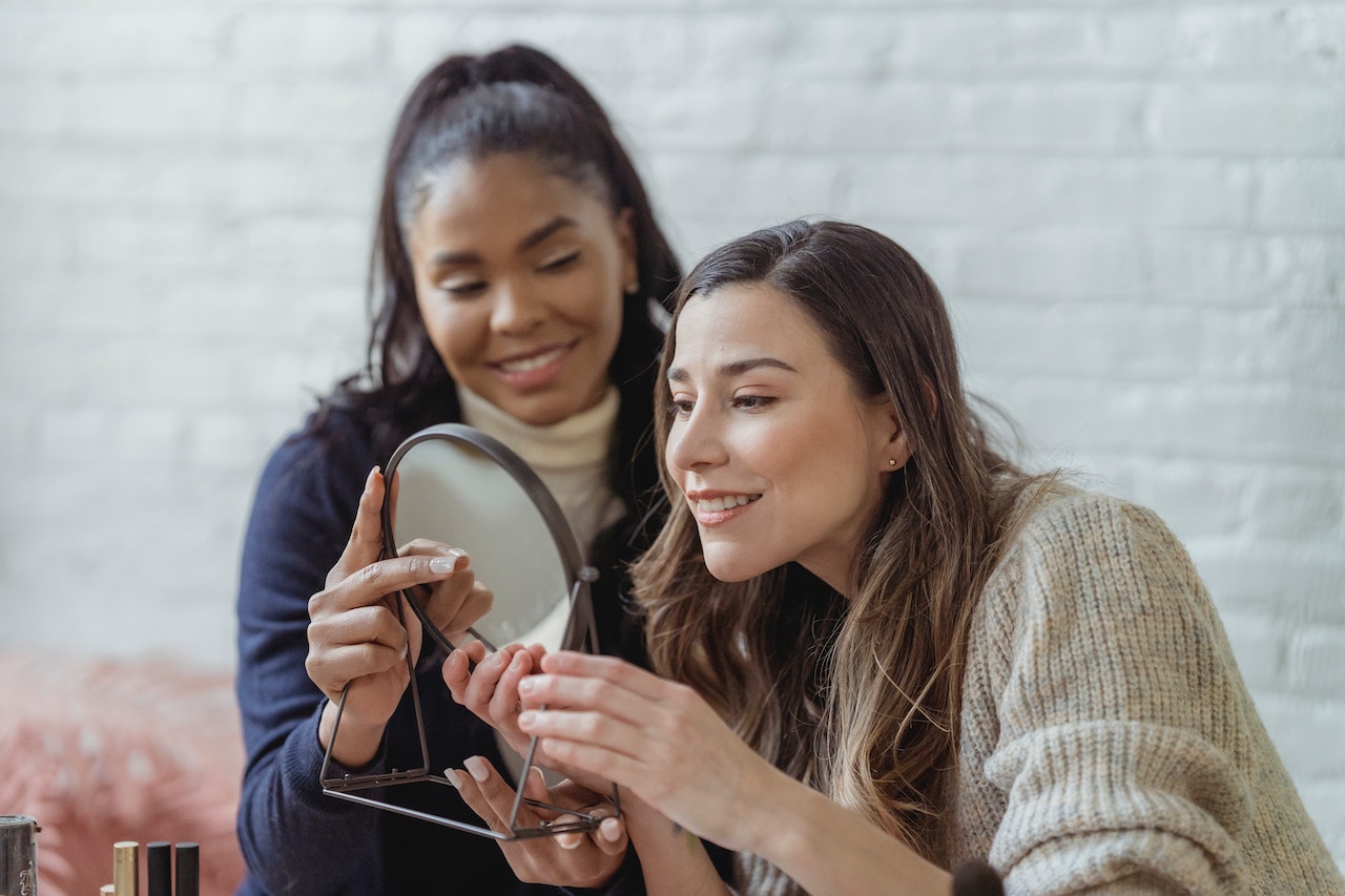 A salon professional shows a client her new style using a hand held mirror.