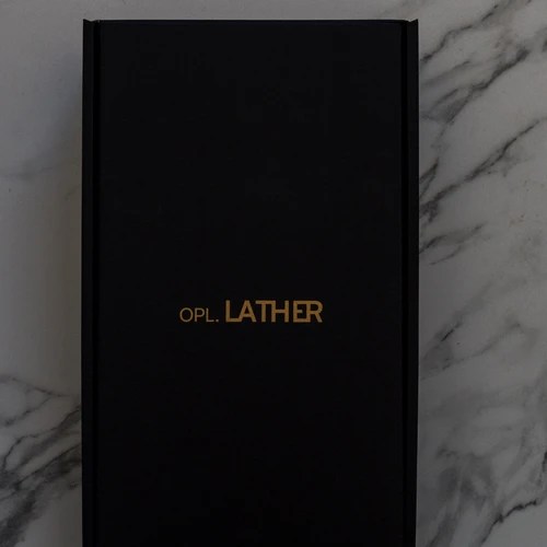Black Opulent Lather skincare gift box with gold logo on marble background